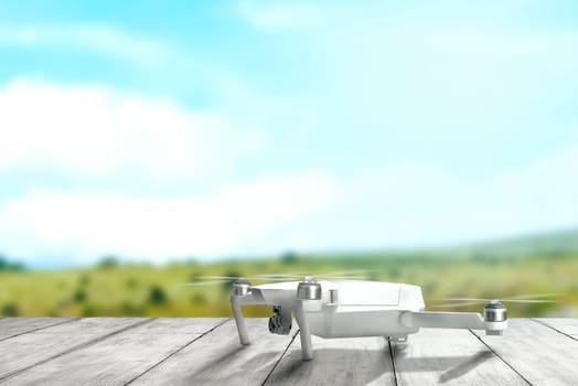 White drone with camera on wooden table ready to flying to the air with blurry landscapes background