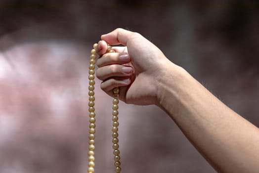 Muslim hands praying with prayer beads over blurry background