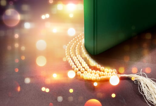 Quran and prayer beads on the table with blurry lights background