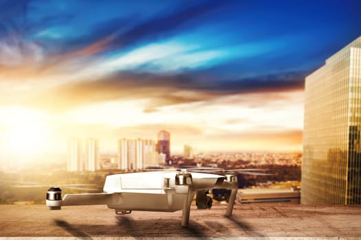 White drone with camera on the rooftop ready to flying to the air with cityscapes at sunset background
