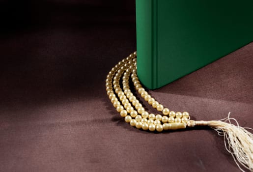 Quran and prayer beads on the table over dark background
