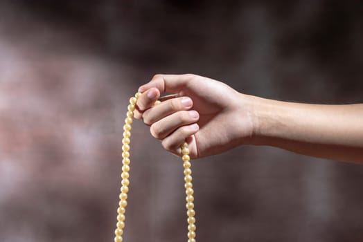 Muslim hands praying with prayer beads over blurry background