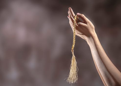Muslim hands praying with prayer beads over blurry background