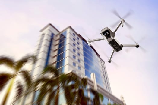 White drone with camera flying to the top of modern building with afternoon background