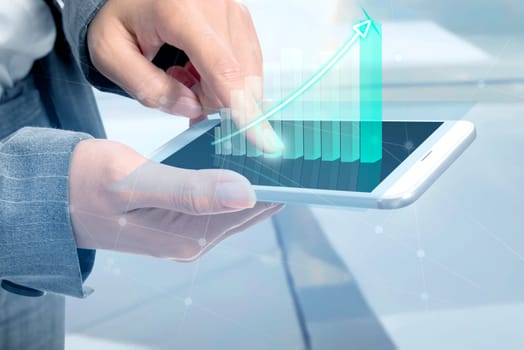 Business woman touch the digital tablet and display the interface of incrased graphs. Digital technology concept