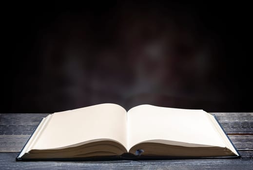 Quran open on wooden table over blurry background