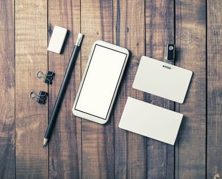 Smartphone and blank stationery on vintage wooden background. Responsive design template. Flat lay.