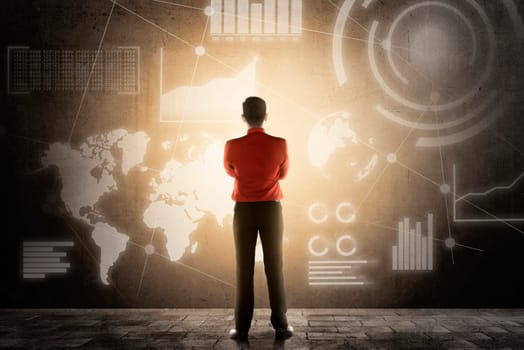 Rear view of asian businessman standing and looking at virtual screen which display the interface of financial chart and world maps. Digital technology concept