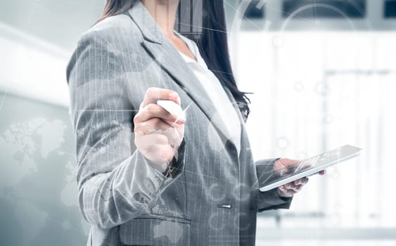 Business woman holding digital tablet and drawing with marker on virtual screen which display the interface of financial chart and world maps. Digital technology concept