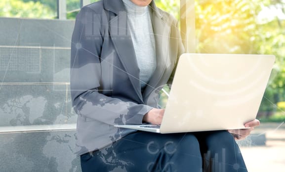 Business woman working using laptop with virtual screen which display the interface of financial chart and world maps. Digital technology concept