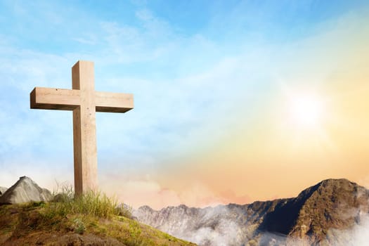 Christian cross on the of mountain with clouds fog over sunrise background