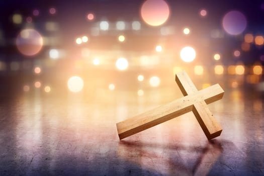 Christian cross on the concrete floor with blurry lights over bright background