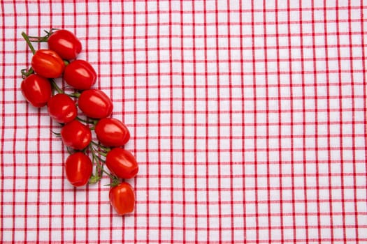 Healthy food background. Top view of fresh red cherry tomatoes on a red checkered napkin or towel. Place for your design. Concept health.