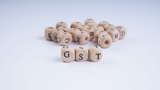 GST inscription on wooden alphabet over white background with selective focus