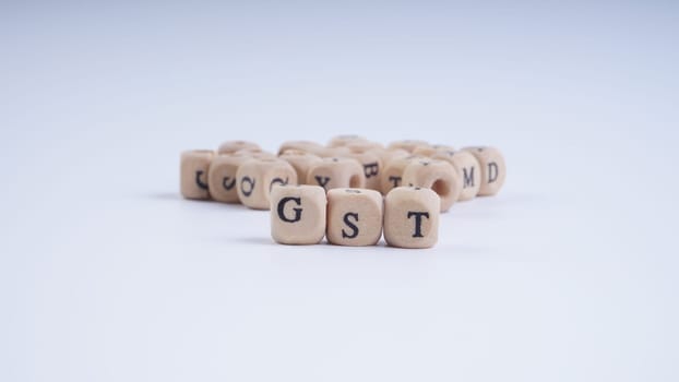 GST inscription on wooden alphabet over white background with selective focus