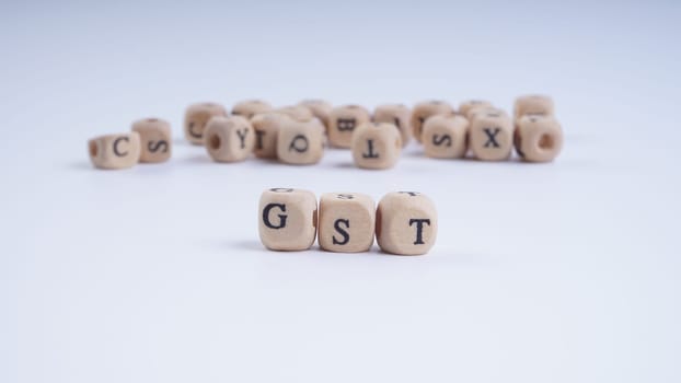 GST inscription on wooden alphabet over white background with selective focus