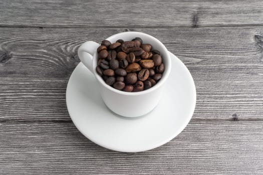 Coffee cup and coffee beans on wooden background. Top view and selective focus