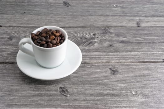 Coffee cup and coffee beans on wooden background. Top view and selective focus