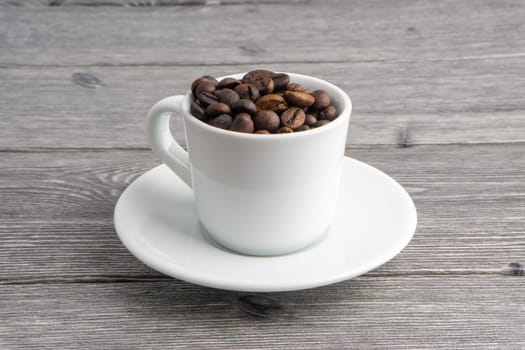 Coffee cup and coffee beans on wooden background. Top view and selective focus