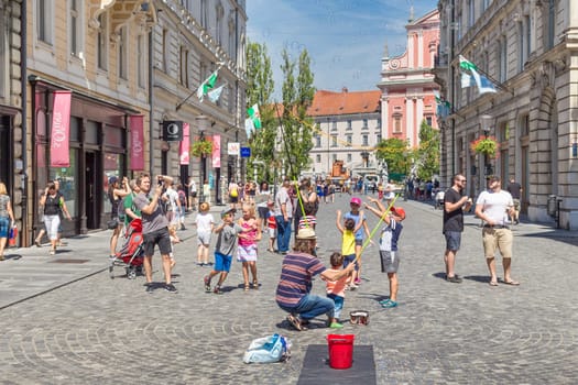 Ljubljana, Slovenia - Aug 9, 2016: Urban street artist performing a soap bubble show for children in medieval city center of Slovenian capital Ljubljana in summer on 9th of August, 2016.