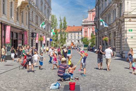 Ljubljana, Slovenia - Aug 9, 2016: Urban street artist performing a soap bubble show for children in medieval city center of Slovenian capital Ljubljana in summer on 9th of August, 2016.