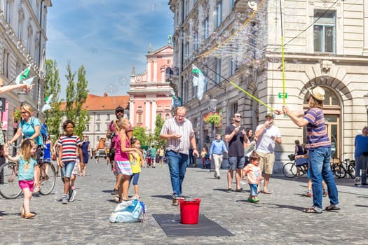 Ljubljana, Slovenia - Aug 9, 2016: Urban street artist performing a soap bubble show for children in medieval city center of Slovenian capital Ljubljana in summer on 9th of August, 2016.