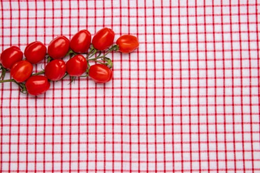 Healthy food background. Top view of fresh red cherry tomatoes on a red checkered napkin or towel. Place for your design. Concept health.