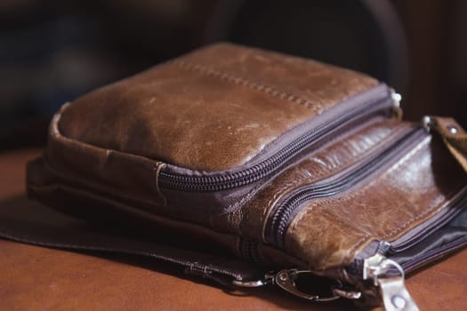 brown leather mens handbag lying on chair