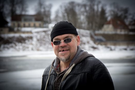 Man with black hat and black sunglasses looking at camera