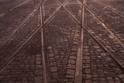 Crossing of tram rails on stone pavement background