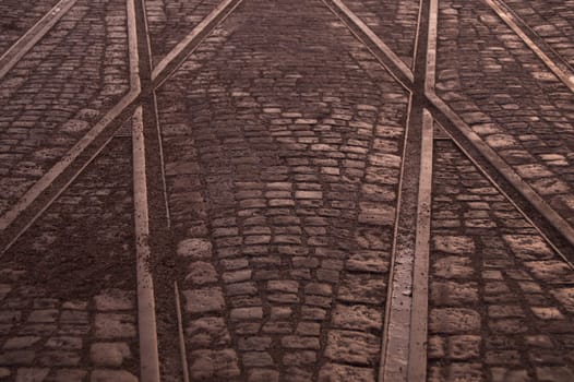 Crossing of tram rails on stone pavement background