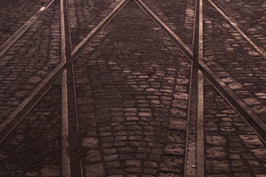 Crossing of tram rails on stone pavement background