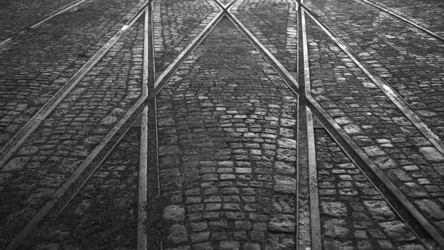 Crossing of tram rails on stone pavement black and white background
