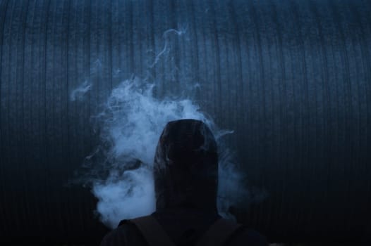 The man smoke an electronic cigarette on the dark background