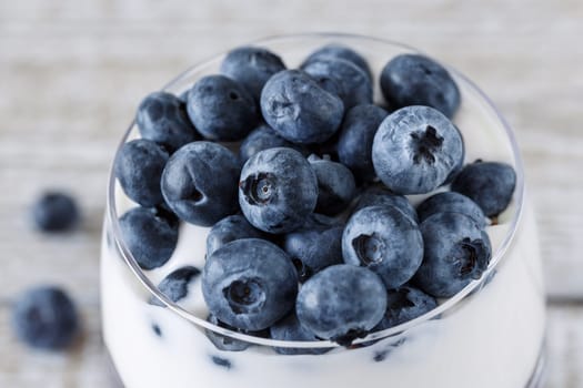 Ripe blueberries on the surface of yogurt in a glass beaker