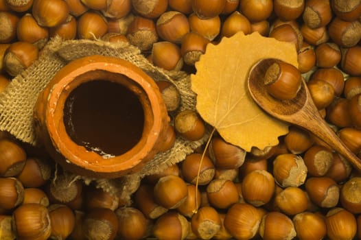 Honey pot with wooden spoon and nuts background