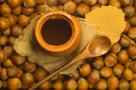 Honey pot with wooden spoon and nuts background