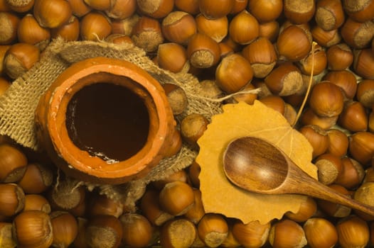 Honey pot with wooden spoon and nuts background