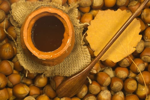 Honey pot with wooden spoon and nuts background