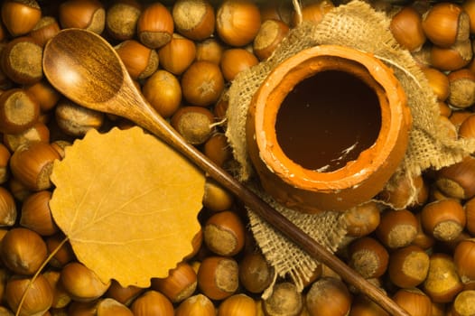 Honey pot with wooden spoon and nuts background