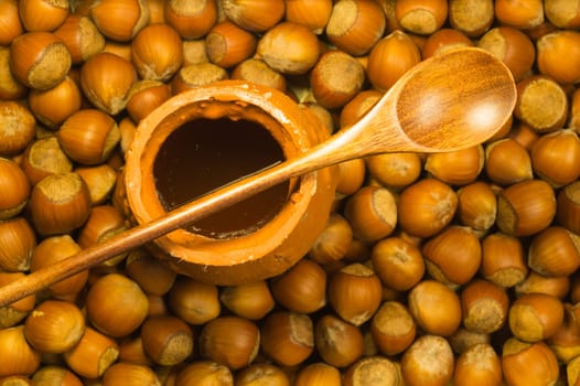 Honey pot with wooden spoon and nuts background