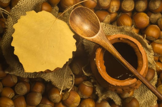 Honey pot with wooden spoon and nuts background
