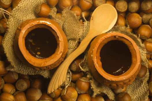 Honey pot with wooden spoon and nuts background