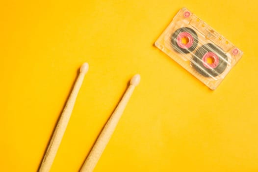 Drumsticks and audio cassette on yellow background