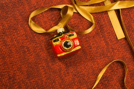 Christmas tree decoration on textile background. Christmas tree toy in a form of a camera. copy space