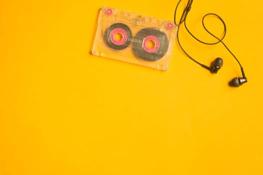 Earphones and retro cassette on yellow background. copy space