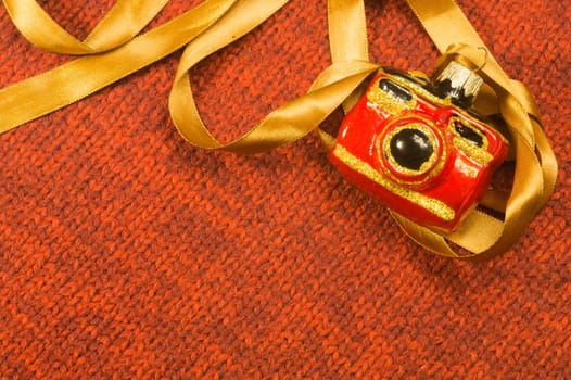 Christmas tree decoration on textile background. Christmas tree toy in a form of a camera. copy space