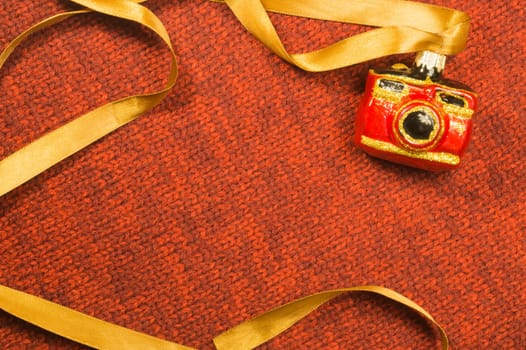 Christmas tree decoration on textile background. Christmas tree toy in a form of a camera. copy space