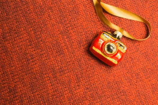 Christmas tree decoration on textile background. Christmas tree toy in a form of a camera. copy space