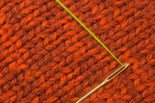 Needle with thread on red textile background. macro view